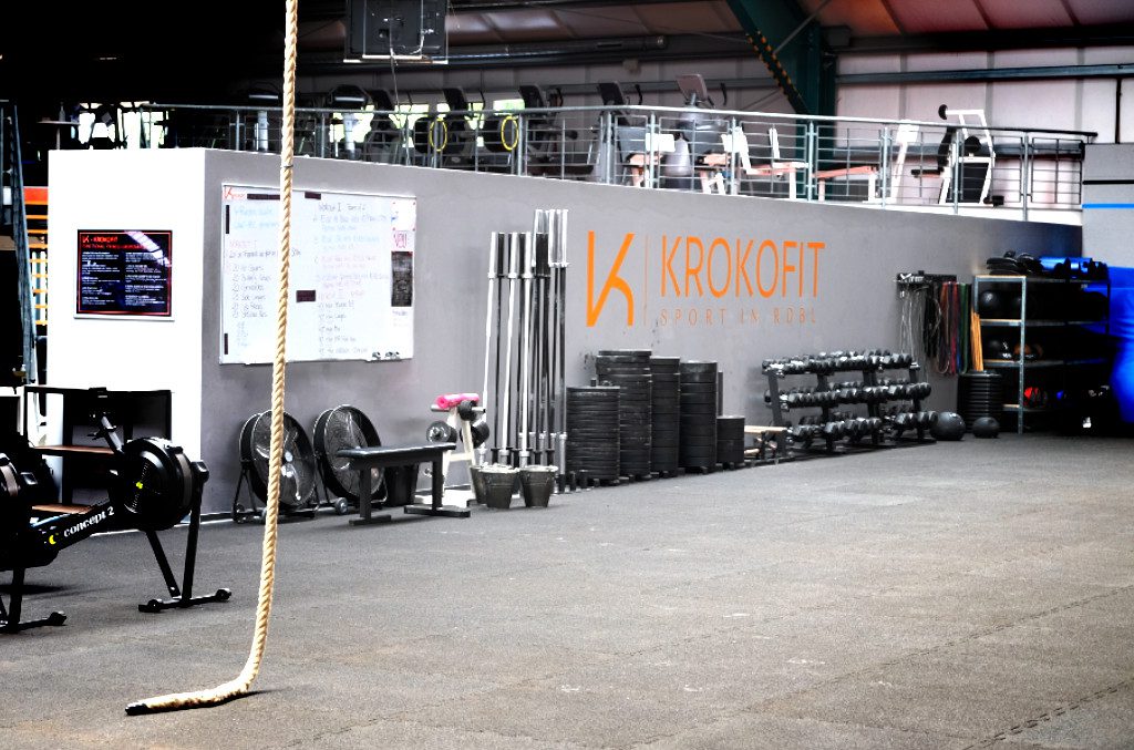 Equipmentwand bei dem Workout Whiteboard mit Langhanteln Chalk Gewichten Dumbells Kurzhanteln Widerstandsbändern StepBoxen Holzstäben für Mobilität Wallballs Medizinbälle Sandsäcke Matten